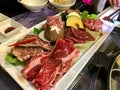 Various types of meat cut into thin slices, mushrooms and vegetables on a white plate, prepared for Korean barbecue