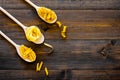 Various types of pasta concept. Fusilli, penne, fettuccine in spoons on dark wooden background top view copy space Royalty Free Stock Photo