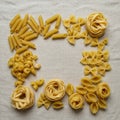Various types of uncooked pasta are arranged on a light-colored fabric background, Royalty Free Stock Photo