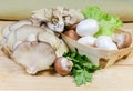 Various uncooked cultivated mushrooms and greens on wooden rustic table