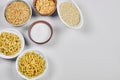 Various uncooked pasta bowls on white background with flour