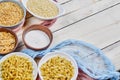 Various uncooked pasta bowls on wooden table with blue tablecloth