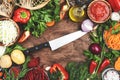 Various uncooked vegetables, herbs and spices for healthy cooking and Chef knife on rustic kitchen wooden table, top view. Royalty Free Stock Photo