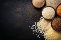 Various varieties: brown coarse rice and white thai jasmine rice in a wooden bowl, dark backgraund, flat lay