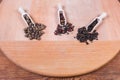 Various whole peppercorns in different wooden spice spoons and beside