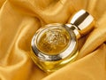 Glass bottle of Versace Eros Pour Femme perfume against gold colored silk satin folds. Produced by Gianni Versace italian luxury