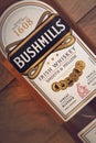 VARNA, BULGARIA - MARCH 16, 2020: Bushmills whiskey bottle on wooden background, close up. Bushmills whiskey distillery was