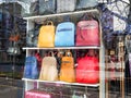 Modern fashionable red, blue and yellow leather handbags in a window of a haberdashery shop on a sunny spring day