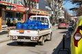 A small open body truck carries blue cylinders with compressed gas to customers. City delivery of gas cylinders. Real city life