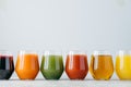 Vartiety of oranganic drink in glasses. Assorted multicolored juice in jar standing at row against white background, empty space