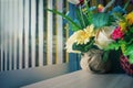 Vase with artificial multicolored flowers beside the window. Royalty Free Stock Photo