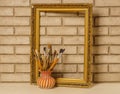 Vase with artistic brushes and the frame on the background of old white brick wall Royalty Free Stock Photo