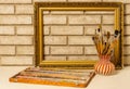 Vase with artistic brushes, pastels and the frame on the background of old white brick wall Royalty Free Stock Photo