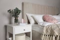 Vase with eucalyptus branches, book and candles on nightstand in bedroom