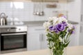 Vase with beautiful flowers in kitchen interior.