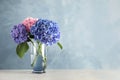 Vase with beautiful hortensia flowers on light table against color background. Space for text Royalty Free Stock Photo