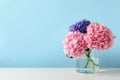 Vase with beautiful hortensia flowers on white table against light blue background. Space for text Royalty Free Stock Photo