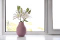 Vase of beautiful lilies on windowsill indoors