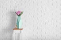 Vase with beautiful pink flowers on stool near white brick wall Royalty Free Stock Photo