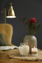 Vase with beautiful protea flowers and burning candles on wooden table indoors. Interior elements Royalty Free Stock Photo