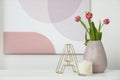 Vase with beautiful tulips, burning candle and decorative letter on table indoors, space for text. Interior elements Royalty Free Stock Photo