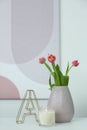 Vase with beautiful tulips, burning candle and decorative letter on table indoors, space for text. Interior elements Royalty Free Stock Photo