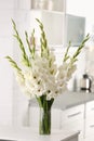 Vase with beautiful white gladiolus  on wooden table in kitchen Royalty Free Stock Photo