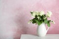 Vase with bouquet of beautiful flowers on table against color background Royalty Free Stock Photo