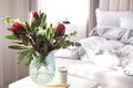 Vase with bouquet of beautiful Protea flowers on white table in bedroom