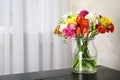 Vase with bouquet of spring freesia flowers on table in room Royalty Free Stock Photo