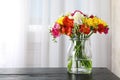 Vase with bouquet of spring freesia flowers on table in room. Royalty Free Stock Photo