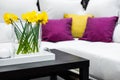 Vase with daffodil flowers in front of white sofa