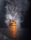 Vase, decorated with twine, with branches of a tree in a smoke croque