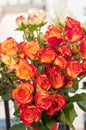 Vase filled with long stemmed orange and red colored baby roses Royalty Free Stock Photo