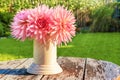Vase with flowers dahlias in the yard on an old wooden table. Bouquet of pink flowers outdoors in the sunlight Royalty Free Stock Photo