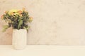 Vase of flowers. Rustic vase with orange roses and yellow chrysanthemums. White background, empty place, copy space. Vintage tinte