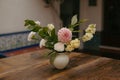 a vase with flowers sitting on a table in front of a tiled wall Royalty Free Stock Photo