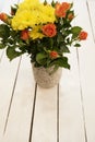 Vase of flowers on a white rustic table. Top view. Rustic vase with orange roses and yellow chrysanthemums. White background, empt Royalty Free Stock Photo