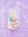 A vase in the form of a bag with pastel candles on a pale lilac background with pearls