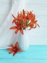 Vase orange lily retro holiday composition on a wooden background textiles