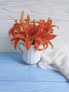 Vase orange lily on a wooden background textiles
