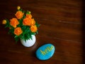 Vase with orange spring summer flowers Trollius asiaticus and blue stone with word hello on wooden table background Royalty Free Stock Photo