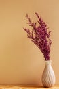 Vase of Pink misty blue dry flowers on wooden table