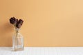 Vase of red dry rose flowers on white table. orange wall background. copy space Royalty Free Stock Photo