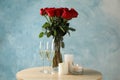 Vase with red roses, glasses of champagne and candles on table, space for text Royalty Free Stock Photo