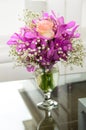 A vase of roses in a bouquet of orchids on a glass table