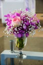 A vase of roses in a bouquet of orchids on a glass table outdoor Royalty Free Stock Photo