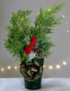 A vase with thuja branches and a pine cone is decorated with a golden rosette and fairy lights Royalty Free Stock Photo