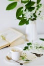 Vase with White Flowers Bird Cherry Tree, Morning, Cup with Coffee, Old Book Royalty Free Stock Photo