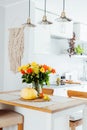 A vase of yellow and orange rose flowers, fresh pumpkin, apple and pear on a kitchen table counter with white modern Royalty Free Stock Photo